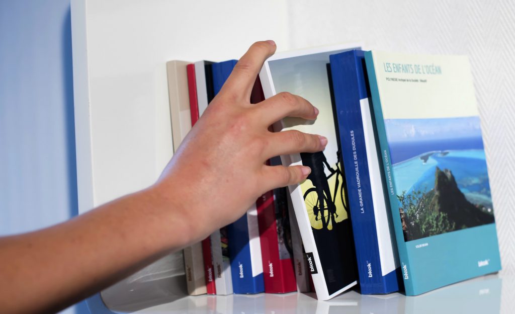 Books on a shelf, a woman's hand is picking one up